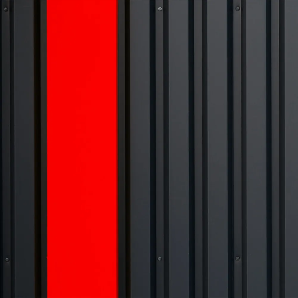 Close-up of a dark metal wall with a single bright red vertical panel.