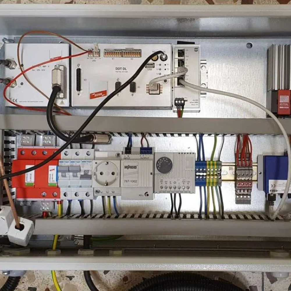 Electrical control cabinet with mounted devices, circuit breakers, terminal blocks, power supply, and connected cables inside a metal enclosure.