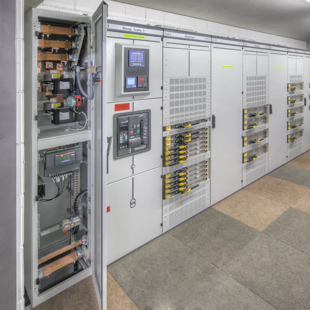 Large electrical switchgear cabinet room with open control panel showing busbars, circuit breakers, and monitoring displays.