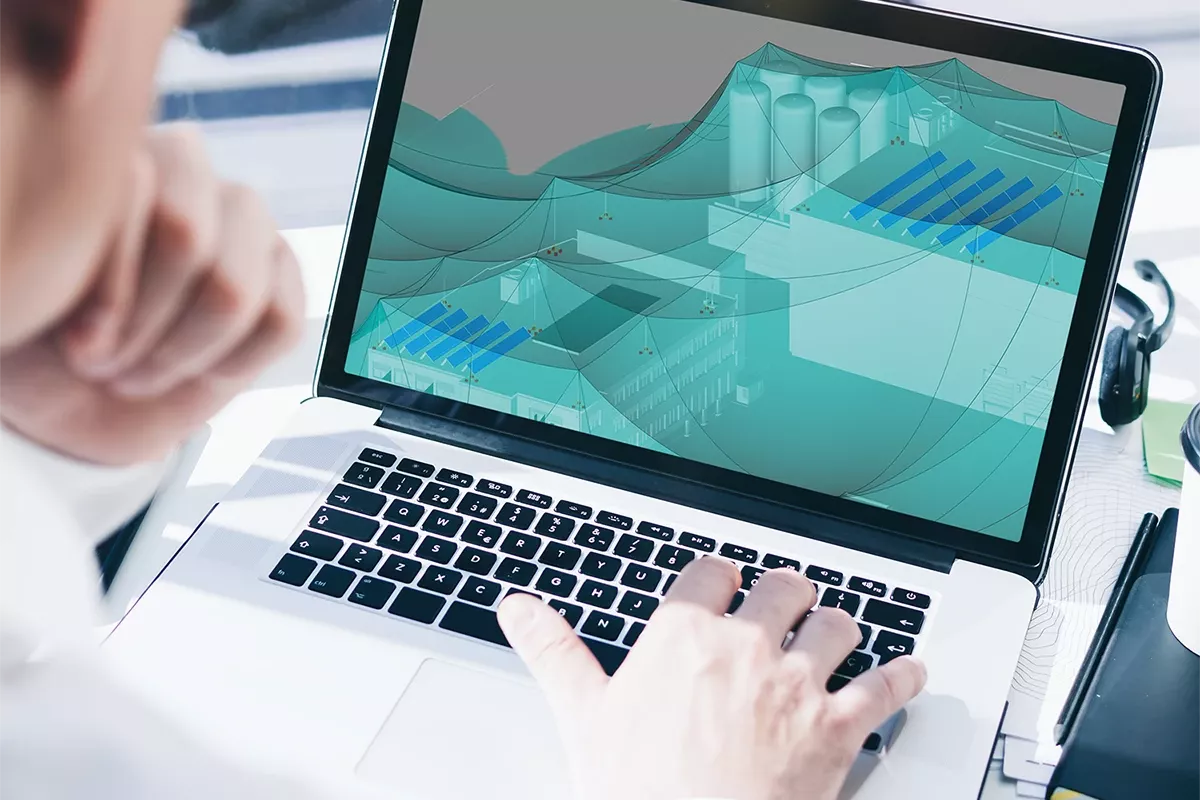 Laptop screen showing electrical planning software with a 3D protection zone model while a person works at the keyboard.